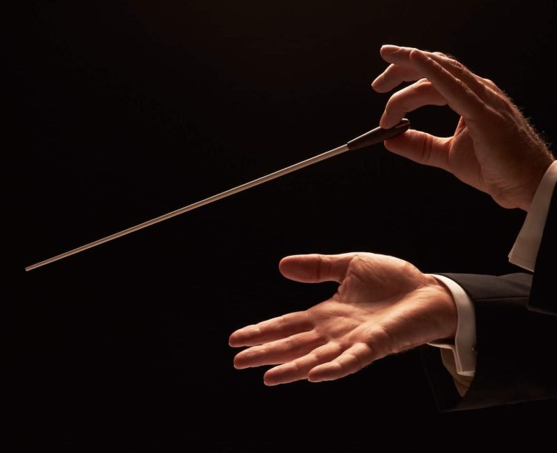 Conductor conducting an orchestra isolated on black background